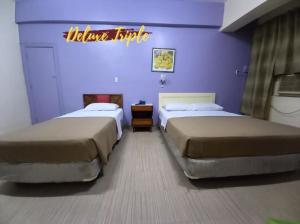 two beds in a room with purple walls at BEST FORTUNE HOTEL at CHINATOWN in Manila