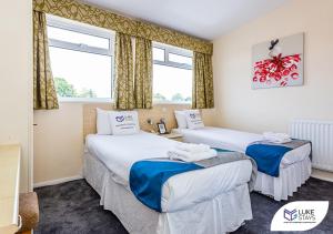 two beds in a room with two windows at Dene Hotel in Newcastle upon Tyne