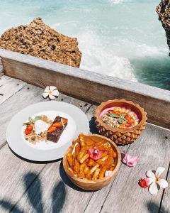 a table with a plate of food and a bowl of food at Le Cliff Bali in Uluwatu +65 photos