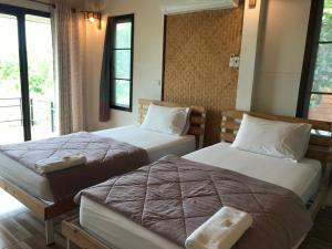 Cette chambre comprend 2 lits et une fenêtre. dans l'établissement บ้านกลางเกาะ รีสอร์ท, à Uthai Thani