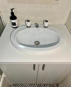 a white bathroom sink with a soap bottle on it at 1 bed room - Cozy unit in Cheltenham +8 photos