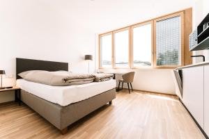 1 dormitorio con 1 cama, escritorio y ventanas en LOOMZ living Self-check-in en Innsbruck