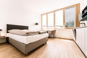 a bedroom with a bed and a desk and windows at LOOMZ living Self-check-in in Innsbruck