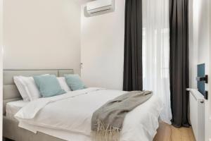 um quarto com uma grande cama branca com almofadas azuis em VD Boutique Apartments No 1 Bucharest em Bucareste