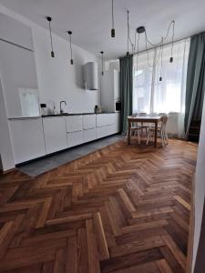 a kitchen with white cabinets and a wooden floor at Apartament z klimatyzacją in Krakow