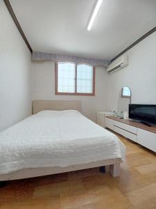 a bedroom with a white bed and a television at Myungsung Youth Town in Gyeongju