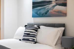 a bed with white pillows and a painting on the wall at Skyvillion - 4 Bed Luxury Apartment with Balcony & Parking in Enfield