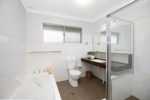 a white bathroom with a toilet and a sink at Hillside Farm in Mittagong