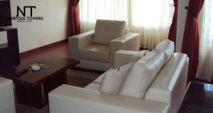 a living room with a white couch and a chair at Norfolk Towers Apartment in Nairobi