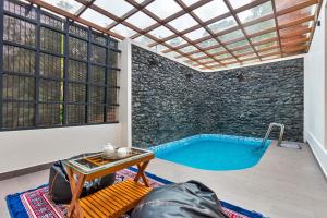 a pool in a room with a stone wall at StayVista at Serene Valley with Bonfire & Badminton in Mananthavady