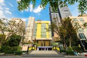 a yellow building in a city with tall buildings at SQ Boutique Hotel Managed by The Ascott Limited in Bangkok
