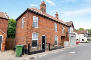 a red brick house with a black fence at Cosy cottage in Norwich in Costessey