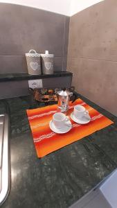 un tavolo con due tazze e piattini su un asciugamano arancione di On the road a Telti