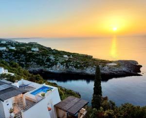 an aerial view of a house with the sun setting over the ocean at BLU SUITE COTTAGE SUL MARE e SWIMMING POOL in Tricase