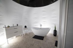 a white bathroom with a tub and a sink at Nomad Hotel & Glamping in Noszvaj