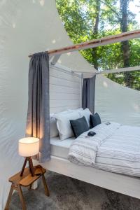 a white bed in a tent with a lamp at Nomad Hotel & Glamping in Noszvaj +54 photos