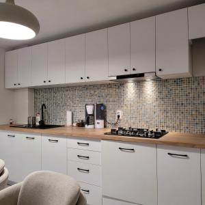 una cucina bianca con armadi bianchi e piano cottura di Hermann Apartment a Cluj-Napoca