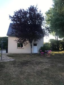 ein kleines weißes Haus mit zwei rosa Stühlen und einem Baum in der Unterkunft Studio meublé près des plages du débarquement in Émiéville