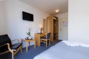 a hotel room with a bed and chairs and a desk at Hotel Rudkøbing Skudehavn in Rudkøbing