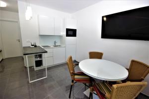 - une table et des chaises blanches dans une chambre avec cuisine dans l'établissement Apartments Smitran, à Banjole