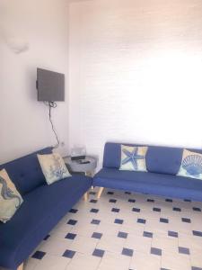 a living room with a blue couch and a tv at Dammuso Cinzia, incantevole fronte mare in Pantelleria