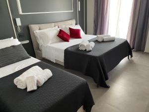 two beds in a hotel room with towels on them at Liberty Lodge in Tropea