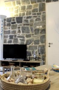 a living room with a stone wall with a television at Cozy house with relaxing backyard in Ermoupoli
