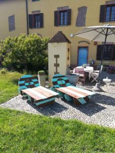 two picnic tables and an umbrella in front of a building at B&B Il Pioppo E La Fonte in Castello d'Agogna