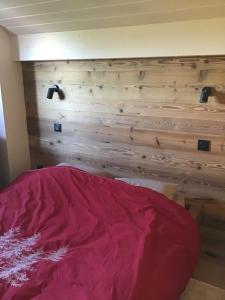 a bedroom with a wooden wall with a red bed at Duplex Bellevue in Gérardmer