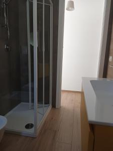 a glass shower in a bathroom with a wooden floor at Casa simone 2 in Conversano