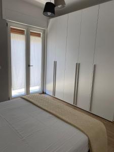 a bedroom with a bed with white cabinets and two windows at Casa simone 2 in Conversano