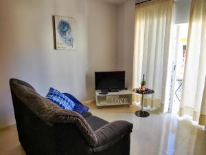 a living room with a chair and a television at Puesta de Sol Rentals 3CR in Playa de San Juan