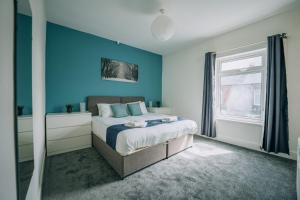 a bedroom with a bed with blue walls and a window at Barron House By Horizon Stays in Darlington