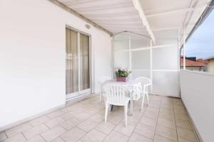 eine weiße Terrasse mit einem Tisch und Stühlen auf dem Balkon in der Unterkunft Residence Barusso in Alassio