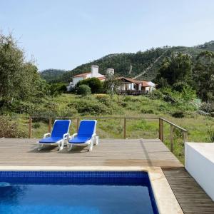 two blue chairs sitting on a deck next to a swimming pool at Monte dos Cachoupos in São Luis