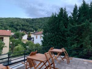 une table et des chaises en bois sur un balcon arboré dans l'établissement Residence Rokia, à Royat