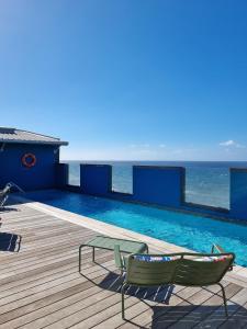 a swimming pool with two chairs and the ocean at DINA MORGABINE SAINT DENIS in Saint-Denis