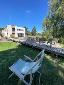 a chair sitting in the grass next to a wooden deck at La Maison Devant La Prairie de 4 à 40 personnes in Griesheim-près-Molsheim