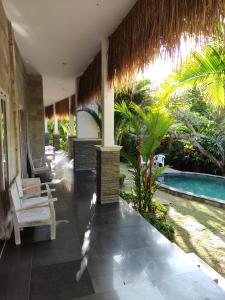 a resort with a swimming pool and a patio with chairs at Karma Backpacker in Uluwatu
