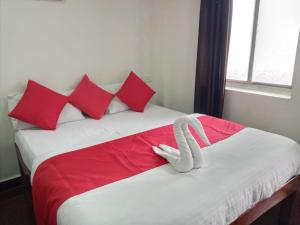 Hotel City Comfort في مادغاون: ثعبان أبيض ملقي على سرير مع وسائد حمراء
