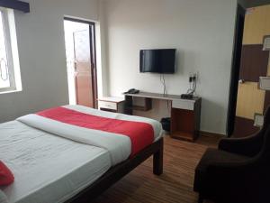 Hotel City Comfort في مادغاون: غرفة نوم بسرير ومكتب مع تلفزيون