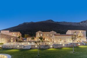 a large building with a lawn in front of a mountain at Salvia Areopolis All Suite Hotel in Areopoli