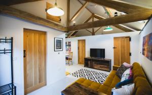 a living room with a couch and a tv at 17th Century Cartshed Nestled In Welsh Countryside in Pandy