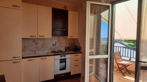 eine Küche mit weißen Schränken und einem Balkon in der Unterkunft Appartamento Nuccia - Box Auto Gratuito e Biancheria Inclusa in Pietra Ligure