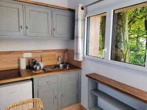 a kitchen with gray cabinets and a sink and a window at Le Refuge de la Doucette in Paimpont
