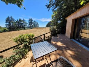 una terraza de madera con mesa y 2 sillas. en Le Refuge de la Doucette en Paimpont