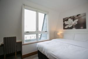 a white bedroom with a bed and a window at Parnell Boulevard Apartments in Dublin