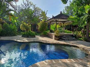 een zwembad in een tuin met een tuinhuisje bij Rumah Askara in Lovina