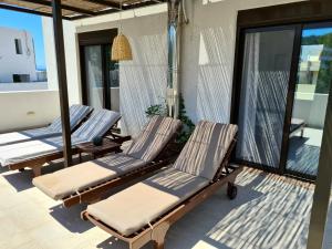 3 Liegestühle auf der Veranda eines Hauses in der Unterkunft Sea Breeze Apartment in Ixia
