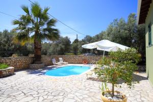 a swimming pool with a palm tree and an umbrella at Elite Escape in Tsoukalades